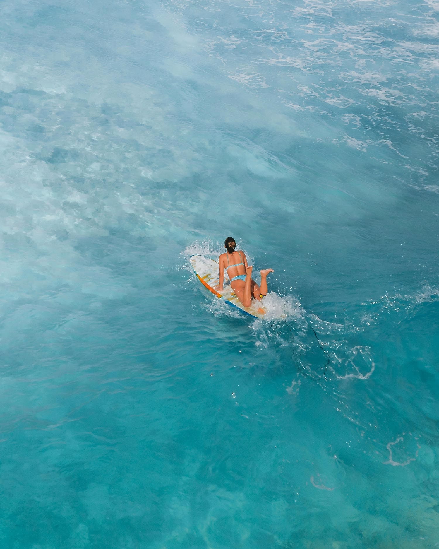 Surfer paddling out on a board into bright blue ocean waves, preparing for an adventure in Puerto Rico’s surf.