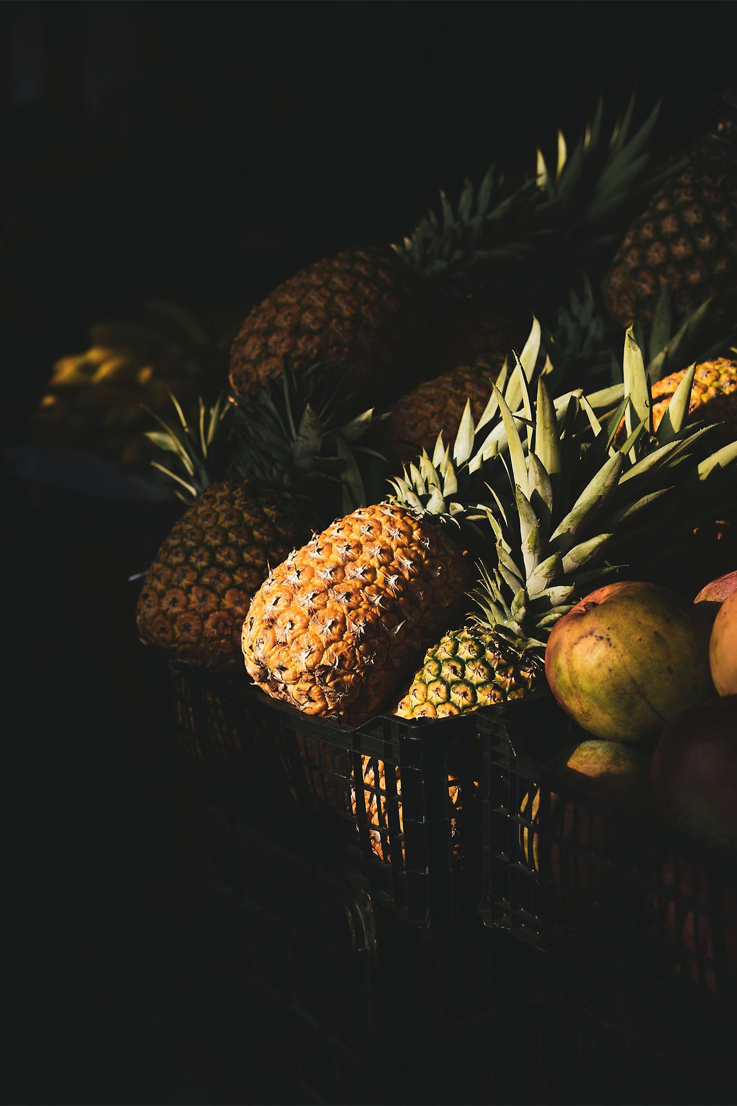 Fresh pineapples stacked at a local Puerto Rico market, highlighted with natural sunlight and deep shadows.