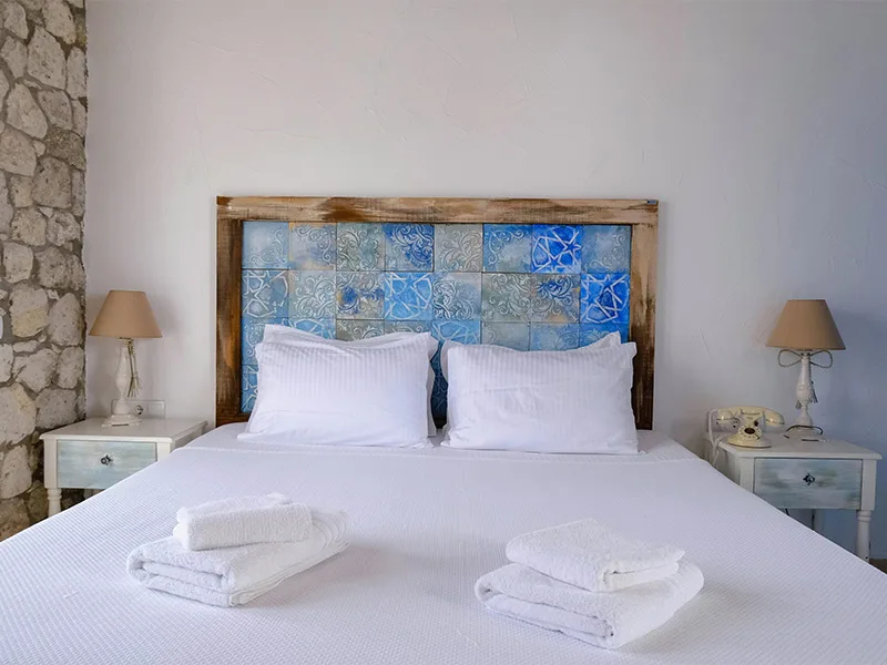 Bright and airy bedroom with white linens and a rustic blue tiled headboard at Coquí Hideaway