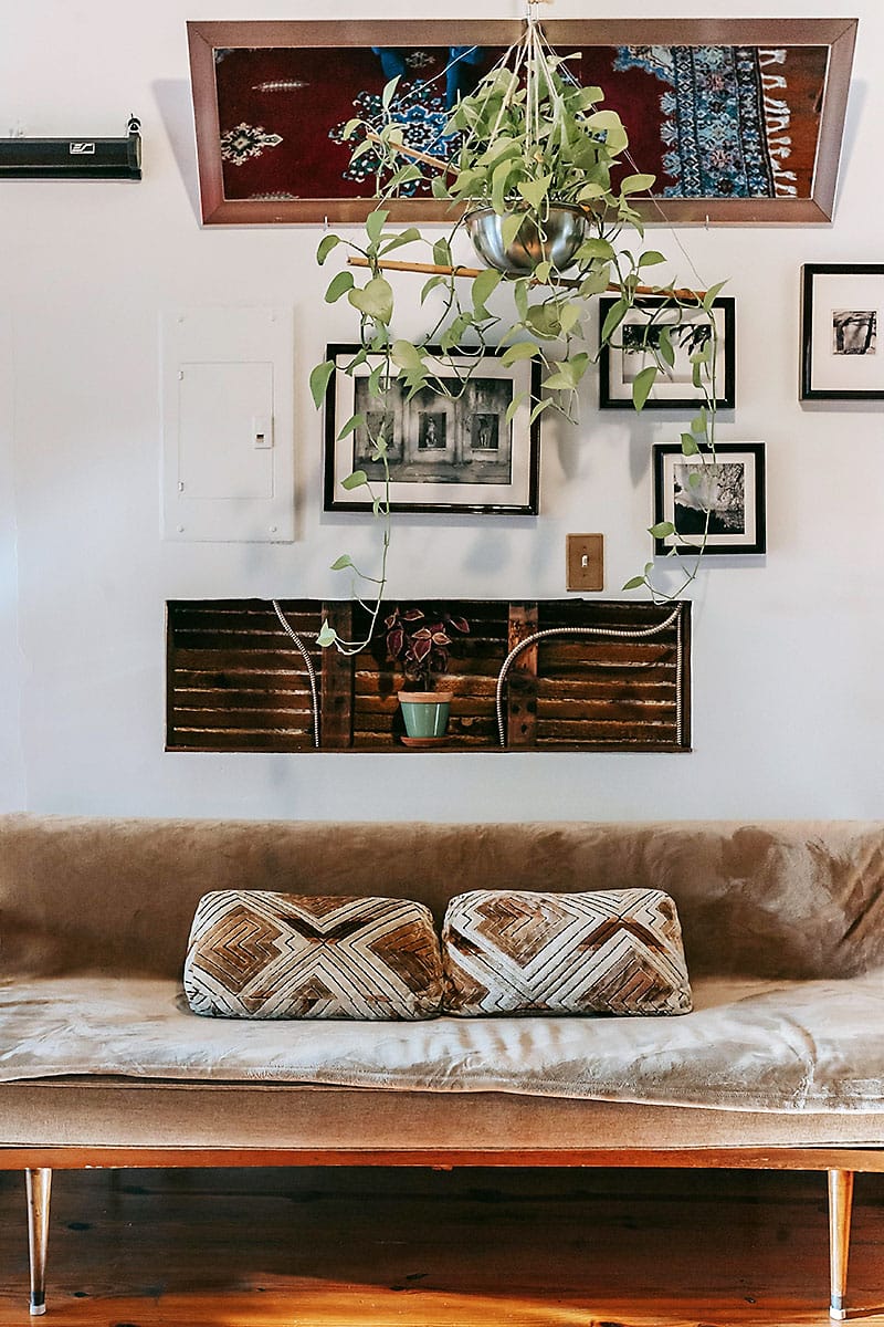Cozy indoor lounge at Coquí Hideaway with vintage sofa, hanging plants, and wall art