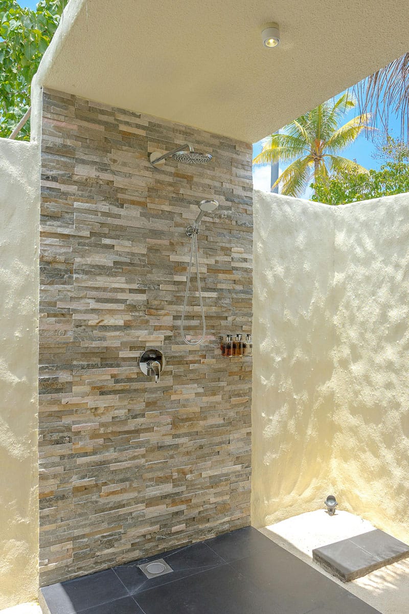Luxury outdoor stone shower at Coquí Hideaway surrounded by tropical greenery